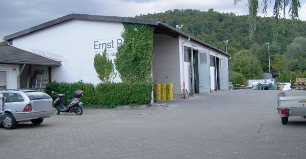 Betriebshof in der Lixstraße: Hallengebäude mit Firmenschriftzug, begrünter Fassade und gepflastertem Hof